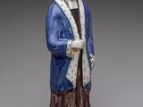 statue d'un homme vêtu d'une robe bleue et d'un chapeau, tenant une canne