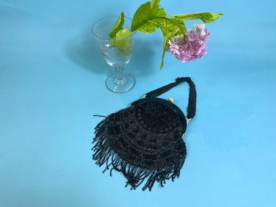 a black purse and a vase with flowers on a blue table