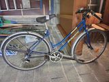 un vélo bleu garé sur le trottoir devant un immeuble