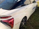 the rear end of a white car is parked in a field