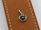 a close up of a leather strap with a green heart charm