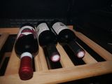 several bottles of wine sit on a wooden rack in an oven