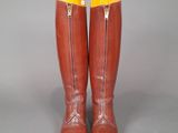 pair of brown boots with yellow zippers on them on a gray surface