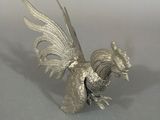 a silver figurine of a rooster on a table