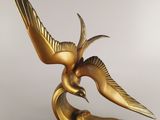 statue of a golden bird on a black base on a white background