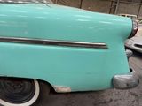 a blue car parked in a garage with other cars in the background