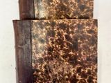 un vieux livre à la couverture marron posé sur une table blanche