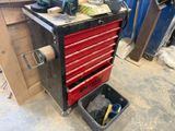 une boîte à outils rouge posée dans un garage, avec des outils dessus