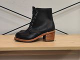 une paire de bottes noires posée sur une étagère en bois