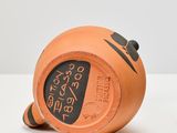 a small orange vase with a clock on it