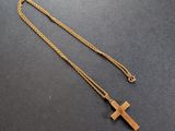 un collier avec une croix en or sur un fond noir