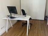 un bureau blanc sur lequel se trouve un ordinateur, dans un coin de la pièce