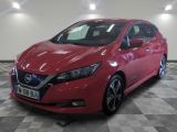 La Nissan Leaf rouge est garée sur un sol à damier.