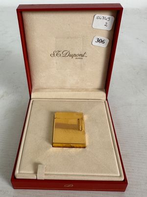 a gold lighter in a red box on a white surface