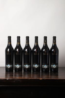 des bouteilles de vin alignées sur une table devant un mur blanc