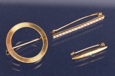 deux broches en or et une épingle sur un fond bleu