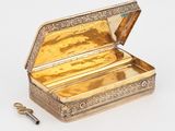 une boîte ancienne en argent avec une clé, posée sur une surface blanche