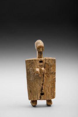 une figurine en bois représentant un homme tenant un bouclier
