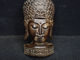a wooden statue of a buddha head on a black surface