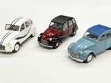 trois petites voitures sont alignées sur une surface blanche