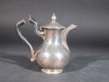 a silver tea pot with a handle on a table