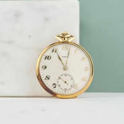 une montre de poche en or posée sur un bloc de marbre