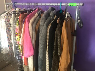 des vêtements suspendus à un portant devant un mur violet