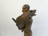 statue d'un homme tenant un poisson, posée sur un socle en bois