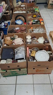 Des cartons contenant des articles variés sont alignés sur le sol d'un magasin