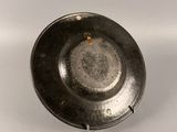 a small metal bowl with a handle on a white surface