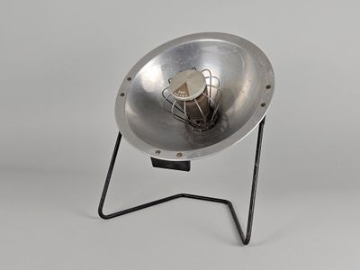 un bol en métal posé sur un socle, surmonté d'une lampe