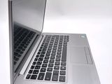 a silver laptop that is open on a white surface