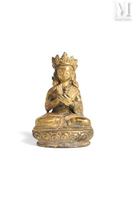 une statue en or représentant une personne assise en position du lotus