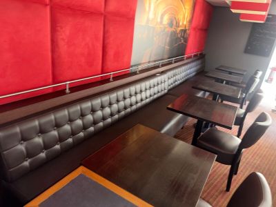 tables and chairs in a restaurant with red walls and a painting on the wall