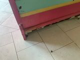 a pink and yellow cabinet in a room with a tile floor
