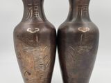 two brown vases sitting on top of each other on a white surface