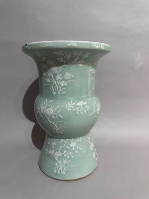 a green vase with white flowers on it