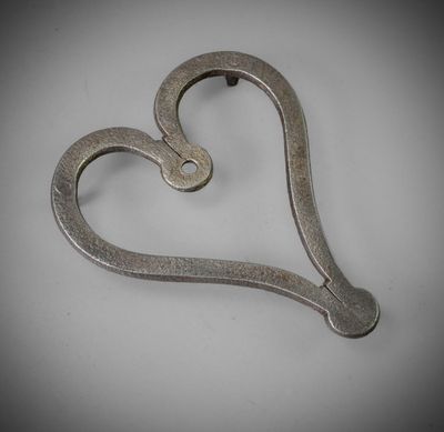 a metal heart shaped object on a white surface