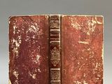 an old book sitting on top of a white table next to a gray wall