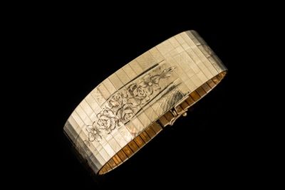 gros plan d'un bracelet en or sur fond noir