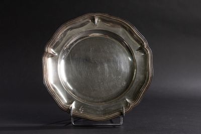 une assiette en argent posée sur un socle, sur fond noir