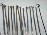 six pairs of surgical instruments are lined up on a white surface