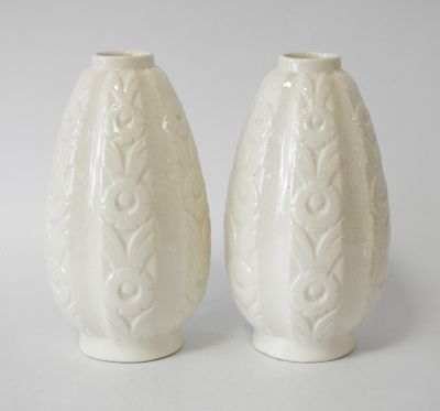 pair of white ceramic vases sitting on top of a white table