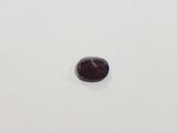 a close up of a red garnet stone on a white surface