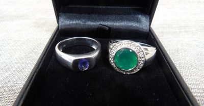pair of emerald and sapphire rings in a black box on a table