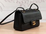 a black leather handbag with gold hardware on a wooden table