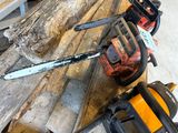 two chainsaws sitting on a wooden table next to each other