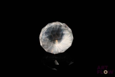 une image représentant une boule de cristal transparente posée sur une surface noire