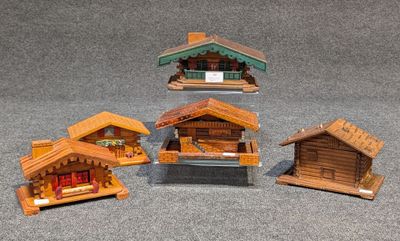 trois petites maisons en bois sont disposées les unes à côté des autres sur une surface grise