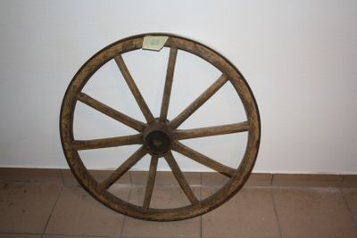 a wooden wagon wheel sitting on the floor next to a wall